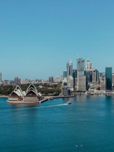 Aerial view of Sydney Opera House with the city skyline in the backdrop under a clear blue sky.